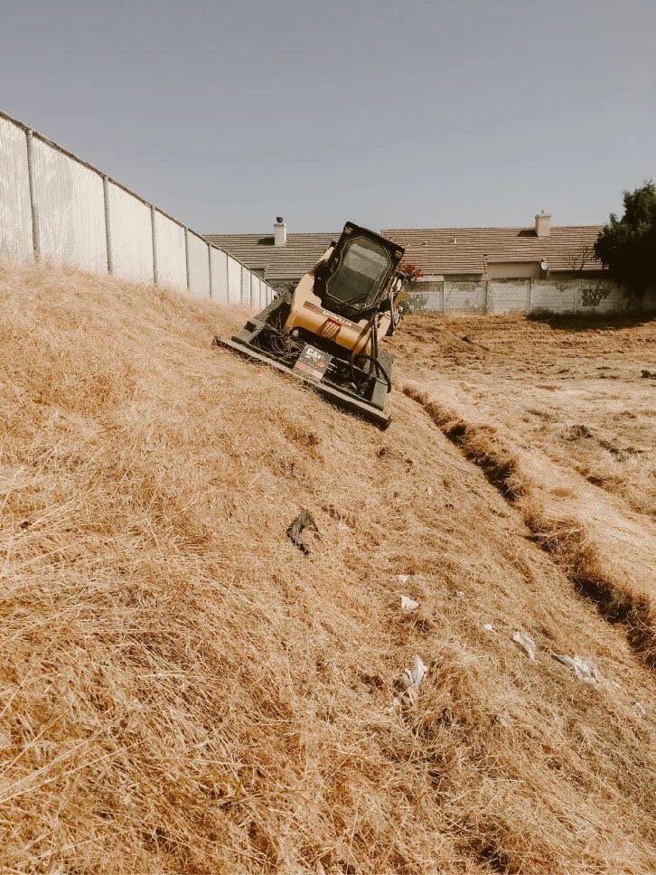 Skid steer mowing a steep dry embankment