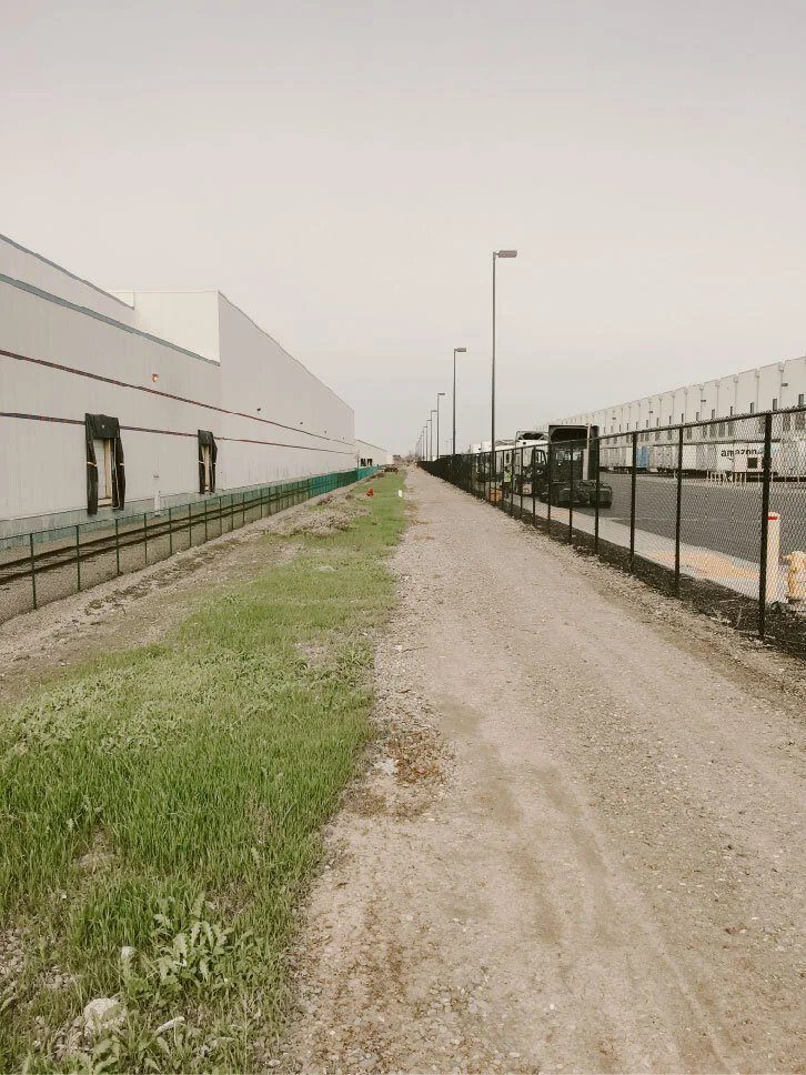 Right of way clearing along a fence line beside an industrial building
